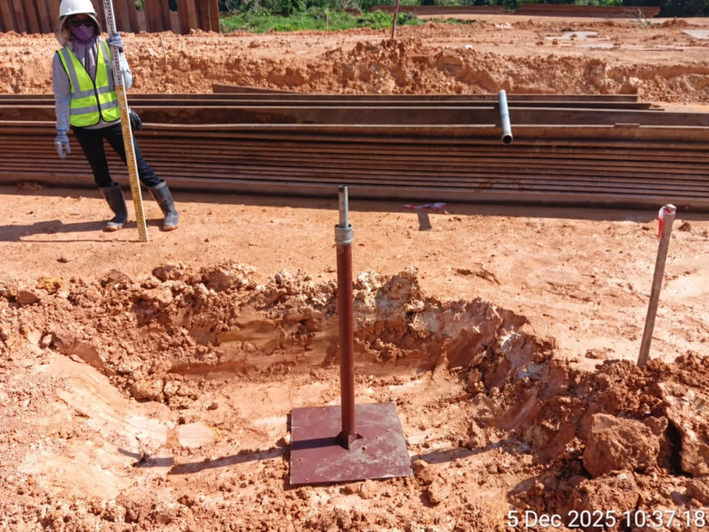 Settlement marker with a base plate positioned in an excavated area